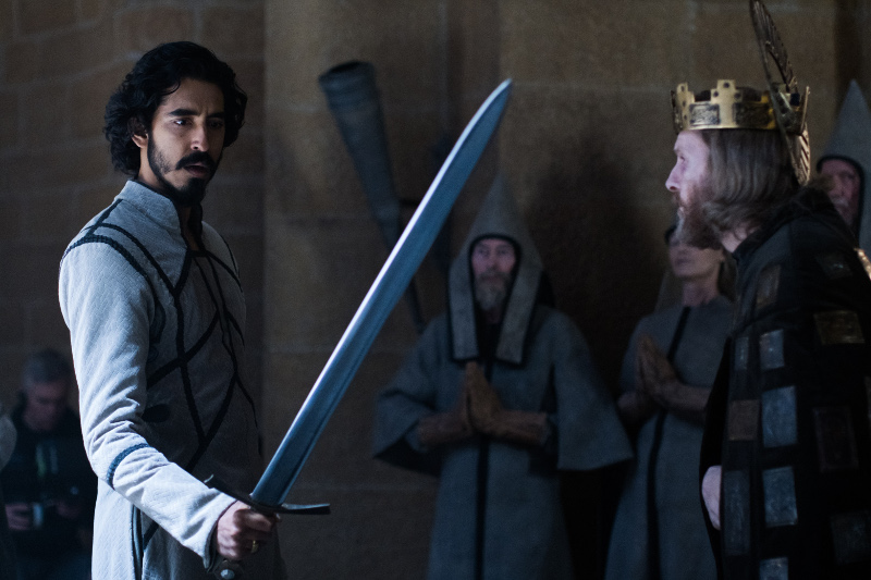 Szenenbild aus THE GREEN KNIGHT - Gawain (Dev Patel)  bekommt das Schwert des Königs (Sean Harris) um gegen den Green Knight zu kämpfen. - © A24